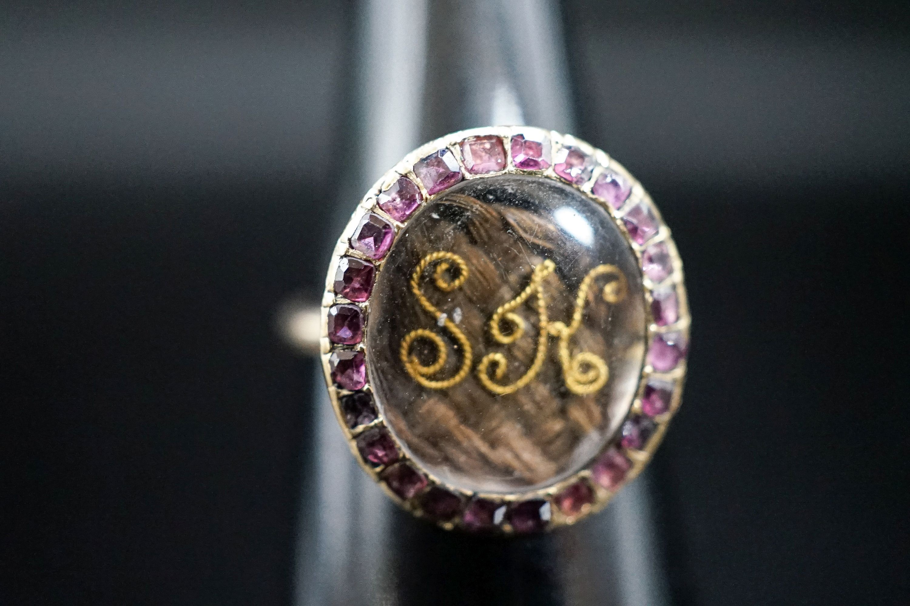 A 19th century yellow metal and gem set mounted glazed mourning ring, with 'S.H.' initialled above plaited hair, size I, gross weight 2.9 grams (adapted).